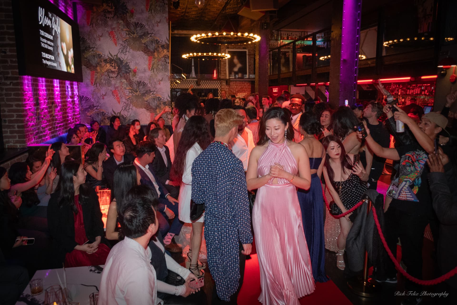 Guests in a gown and a patterned jumpsuit walking the carpet at an Xchange Fashion gala